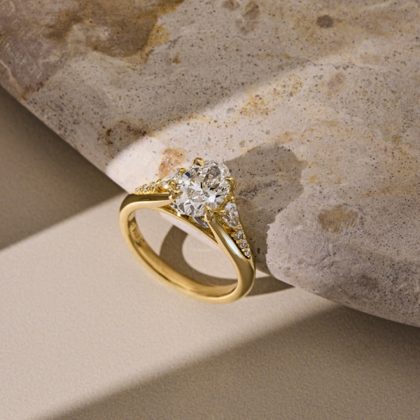 Oval cut Diamond with pear shaped side stones and a yellow gold band